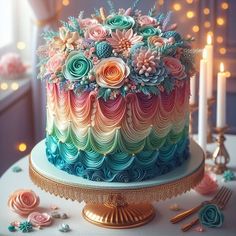 a multicolored cake sitting on top of a table next to candles and flowers