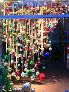 an assortment of christmas ornaments are hanging from the ceiling in front of a store window