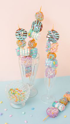 there are many donuts in the glass vases on the table with sprinkles