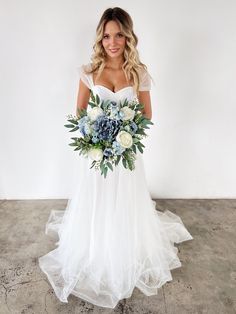 a woman in a white wedding dress holding a blue and white bridals bouquet