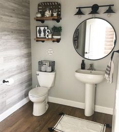 a white toilet sitting next to a sink in a bathroom under a round mirror on a wall