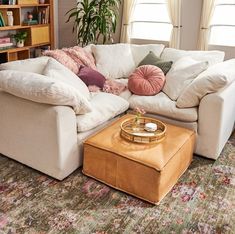 a living room with a couch, ottoman and coffee table in front of a window