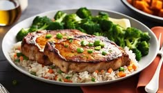 a white plate topped with meat and rice next to broccoli on a table