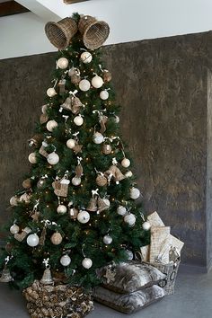 a decorated christmas tree with white and silver ornaments in the corner next to a bed