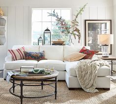 a living room with white couches and pillows on top of the sofa is shown