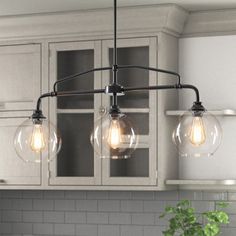 three light bulbs hanging from the ceiling in a kitchen