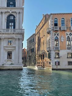 some buildings and water in the middle of a canal with people on boats going down it