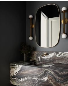 a bathroom sink with an oval mirror above it and marble counter top in the middle