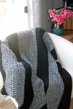 a black and white blanket sitting on top of a couch next to a vase with flowers