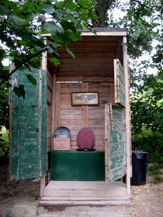 a wooden outhouse with an open door and green steps leading up to the outside