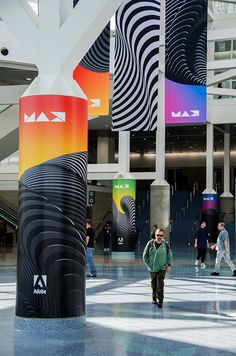 a man is walking through an airport lobby with many colorful banners hanging from the ceiling