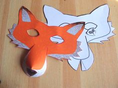 an orange and white fox mask sitting on top of a wooden table next to a computer mouse