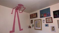 a room with pictures on the wall and paintings on the walls, including a pink sticker