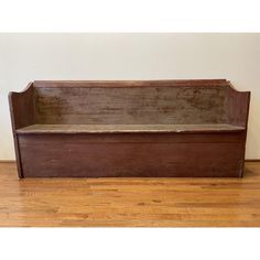 an old wooden bench sitting on top of a hard wood floor next to a wall