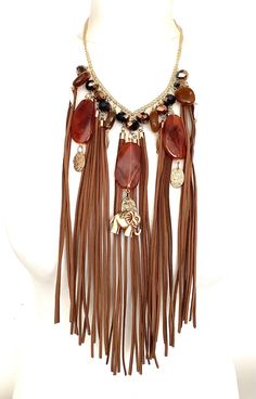 Tan suede tassel and bead statement necklace from Olivia Divine. Long tan suede tassels, beads and elephant charm necklace. Set on a gold tone chain. Adjustable length. Perfect for festivals. Gold Tassel Necklaces For Festival, Chic Brown Dangle Jewelry, Gold Tassel Necklace For Festivals, Gold Beaded Dangle Tassel Necklace, Bohemian Gold Tassel Necklace For Party, Adjustable Fringe Dangle Necklace, Chic Long Tassel Necklaces, Adjustable Elegant Tassel Necklace For Festival, Chic Adjustable Tassel Necklace As A Gift