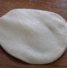 an uncooked pizza dough sitting on top of a wooden table