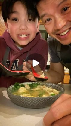 a man and boy eating food at a table with chopsticks in front of them