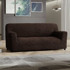 a brown couch sitting on top of a hard wood floor next to a white rug