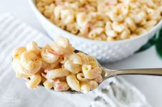 a spoon full of macaroni and cheese next to a bowl of other food