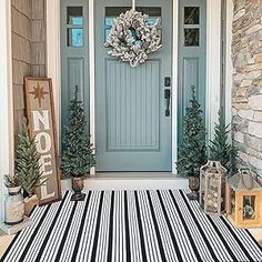 a front porch decorated for christmas with striped rugs and wreath on the door mat