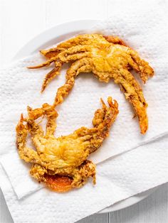 fried food on a white plate sitting on top of a napkin