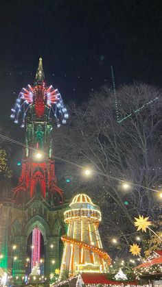 a large clock tower lit up at night with christmas lights on it's sides