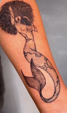 a woman's arm with a mermaid tattoo on it