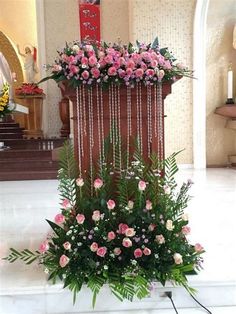 a floral arrangement is displayed on the floor in front of a church alter with pink flowers and greenery