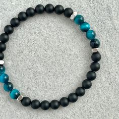 Men's beaded bracelet features: ~ 6mm Matte Onyx beads ~ 6mm Aqua Blue Tiger Eye beads ~ 6mm Stainless Steel spacers ~ Stretchy cord; simply slide bracelet on and off wrist ~ Comes packaged in a re-usable micro fibre pouch To ensure the perfect fit, please use the bracelet sizing instructions found in the photo gallery. Modern Adjustable Stretch Bracelet With Round Beads, Blue Bracelets With 8mm Beads For Everyday, Everyday Blue Bracelets With 8mm Beads, Blue Tiger Eye Bracelet, Bracelets Men, Blue Tiger Eye, Slide Bracelet, Blue Tiger, Tiger Eye Bracelet