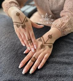 a woman's hands with henna tattoos on her arm and hand, while she is