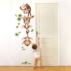 a baby reaching up to the wall with monkeys on it