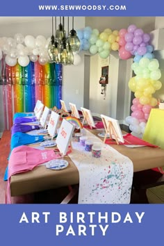 the table is set up for an art party with colorful balloons and paintings on it