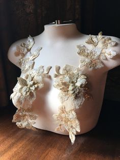 a white mannequin with flowers on it's chest and back, sitting on a wooden floor