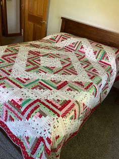 a bed with a quilt on top of it in a room next to a door