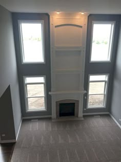 an empty room with three windows and a fireplace