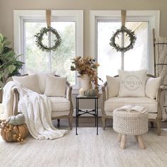 a living room with white furniture and wreaths on the windows