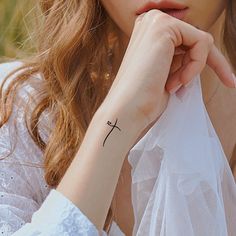 a woman with a small cross tattoo on her wrist