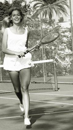 black and white photograph of a woman holding a tennis racquet on a tennis court