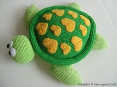 a crocheted turtle with yellow hearts on it's shell is laying down