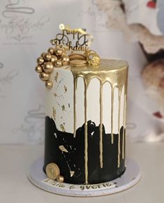 a black and white cake with gold drips on the top is sitting on a plate