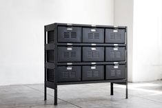 a black cabinet with many drawers in front of a painting on the wall above it