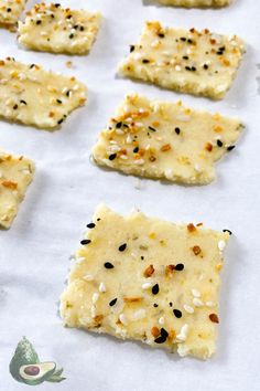 crackers with sesame seeds and seasoning sitting on top of a baking sheet covered in parchment paper