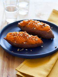 two sweet potatoes on a blue plate next to a glass of water