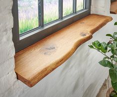 a wooden window sill sitting next to a potted plant