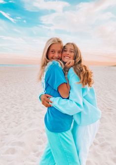 two girls hugging each other on the beach