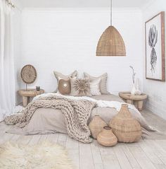 a bed with pillows and blankets on it in a room next to two tables that have baskets