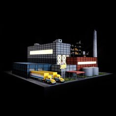 a model of a building with cars parked in front of it and a factory on the other side