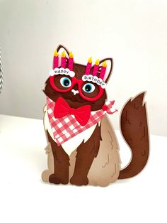 a paper cut out of a cat wearing glasses and a bow tie with birthday candles on its head