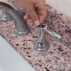 a person's hand is on the handle of a faucet