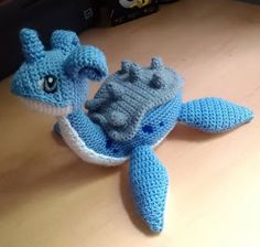 a crocheted blue and white stuffed animal laying on top of a wooden table